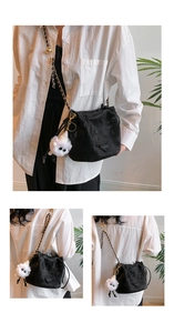 Detail view of black chain bucket bag with fashion logo and plush doll pendant