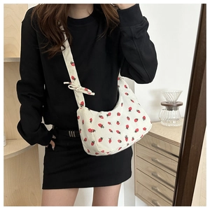 Detalle de bolso medialuna de pana blanca con estampado de fresas y correa con nudo