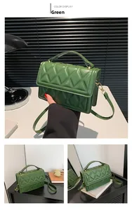Close-up of green quilted square bag with gold hardware and top handle detail