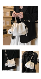 Three-way display of off-white drawstring bucket bag with chain strap and plush charm