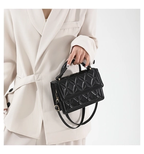Detailed view of black quilted faux leather crossbody bag with gold-tone hardware and handle