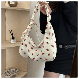 Detalle de textura de pana y estampado de fresas rojas en este bolso de hombro crema