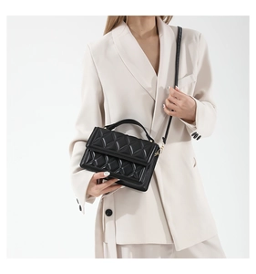 Detail of classic black quilted handbag showing fine diamond stitching and golden hardware