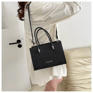 Close-up of black lychee grain handbag with FASHION text and silver metal hardware details