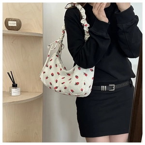 Detail of white corduroy shoulder bag with red strawberry print and bow drawstring strap