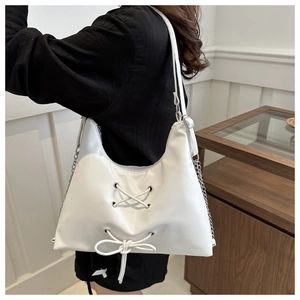 Close-up of white synthetic leather bag featuring lace-up design and silver chain strap