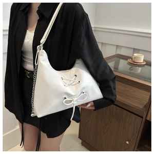 Close-up of white PU leather tote with decorative bow and silver chain strap detail