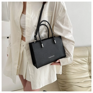 Close-up of black crossbody tote bag with FASHION lettering and slim shoulder strap