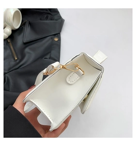 Close-up of small white crossbody bag interior with gold hardware and flap closure detail