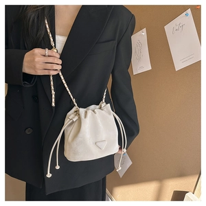 Détail d'un sac seau blanc crème à cordon avec bandoulière chaîne et logo métal