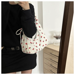 Detalle del bolso hobo de pana blanca con bordados de fresas rojas y textura suave