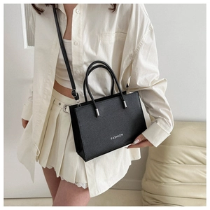 Model wearing a black tote bag with white Fashion text and pebbled leather texture