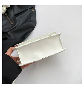 Detail view of the flat bottom and precise stitching on the white faux leather crossbody bag