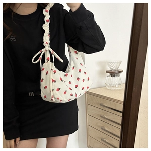 Detalle del bolso de pana blanca con estampado de fresas y correa con lazo decorativo