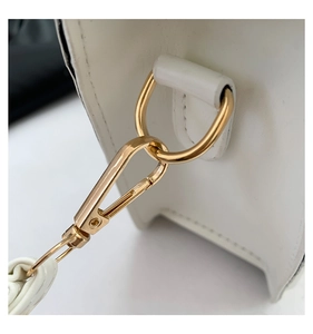 Close-up of premium golden metal buckle and stitching details on a white leather handbag