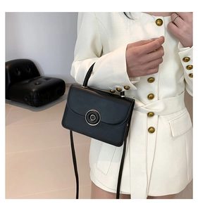 Detail of elegant black matte leather handbag with gold circular ring hardware