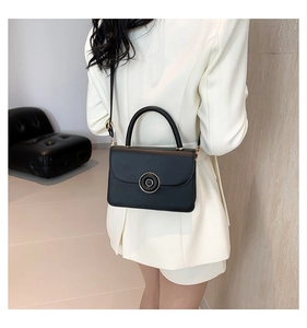 Chic black matte leather crossbody bag with gold round buckle shown on a model