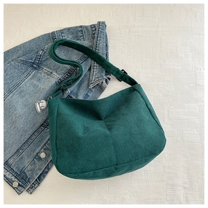 Detail of dark green corduroy shoulder bag texture with cute white dog charm accessory