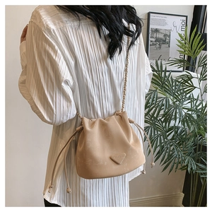 Detail van beige bucket bag met trekkoord en gouden ketting voor dames mode