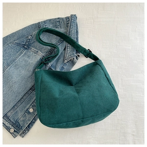 Close-up of green corduroy hobo bag texture with adjustable strap on white background
