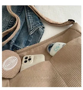 Detail of beige corduroy shoulder bag showing inner space with daily essentials and small pouch