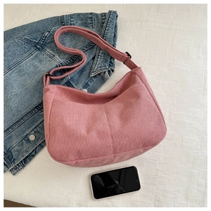 Detailed texture of pink corduroy crescent shoulder bag shown with phone for scale