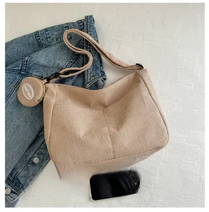 Detail of beige corduroy crescent shoulder bag and small round coin purse with logo