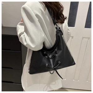 Detail of black PU leather bow shoulder bag with silver chain strap on model