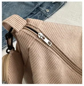 Detail of beige corduroy crossbody bag with smooth silver zipper and matching round pouch