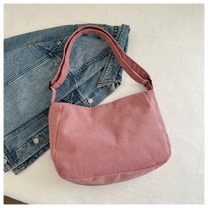 Detail of pink corduroy shoulder bag showing soft ribbed texture and adjustable strap