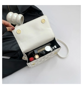 Macro view of white quilted crossbody bag interior showing lipstick and perfume storage