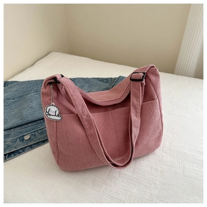 Detail of pink corduroy tote bag with adjustable strap and cute white puppy plush charm