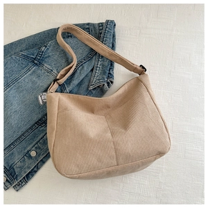 Detail view of the beige corduroy texture and adjustable wide strap of the shoulder bag