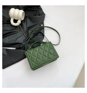 Close-up of deep green quilted crossbody bag with a circular handle on a desk