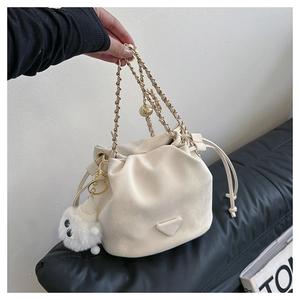 Detail van crèmewitte emmertas met gevlochten ketting en schattige pluche monsterhanger