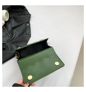 Close-up of deep green leather crossbody bag featuring gold magnetic buckles and interior