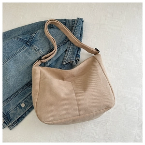 Detail of khaki corduroy shoulder bag with adjustable strap on denim jacket background