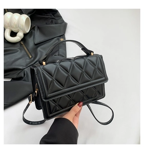 Detail of classic black quilted crossbody bag showing textured diamond stitching and metal hardware