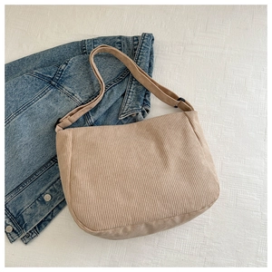 Detail of light khaki corduroy crescent bag showing material texture on denim background