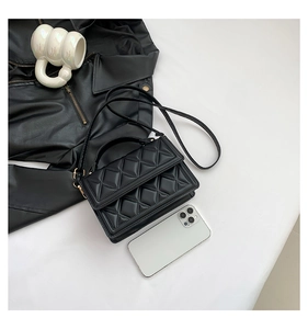 Detailed close-up of a black quilted leather mini handbag with a top handle and shoulder strap