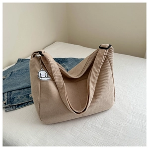 Detail of khaki corduroy tote bag featuring adjustable wide strap and cute puppy pendant
