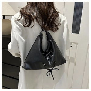 Close-up of matte black leather backpack with silver eyelets and drawstring pleat detail