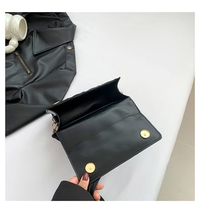 Detail of black faux leather handbag with dual gold magnetic clasps in open view