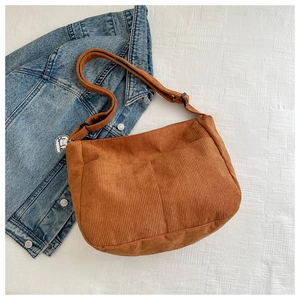 Detail of brown corduroy hobo bag featuring two front pockets and adjustable strap