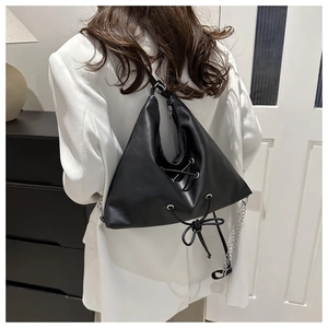Detail of black triangular PU leather tote with cross-lace design and silver chain strap