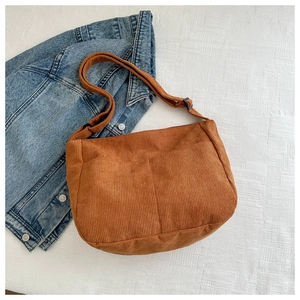 Detail of brown corduroy crossbody bag texture with adjustable strap on denim jacket