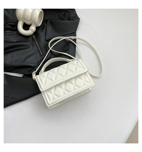 Detail of white quilted crossbody bag with golden hardware and top handle for women