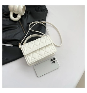 Detail of white quilted crossbody bag with gold hardware and adjustable strap
