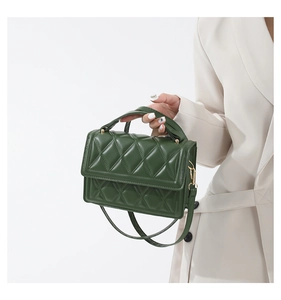Detailed view of dark green crossbody bag with classic diamond quilted pattern and gold hardware