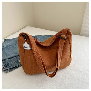 Close-up of brown corduroy crossbody bag with adjustable strap and cute dog keychain